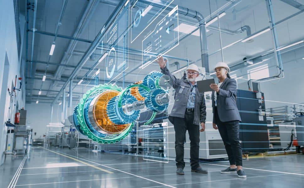 Engineering professionals reviewing a holographic mechanical model with digital overlays in a modern industrial facility